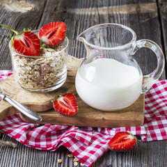 Oat flakes, milk, strawberries for breakfast on a gray wooden background