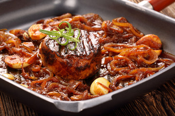 Grilled pork chop with onion on the pan on wooden background