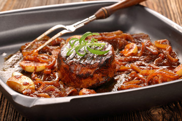 Grilled pork chop with onion on the pan on wooden background