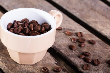 Coffee seed in beige cup on wooden plank