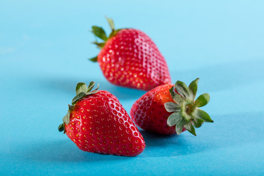 Three juicy strawberry on blue background
