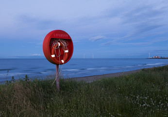 Red coloured Life Buoy on Cambois Beach on the coast of Northumberland, England, Uk. Image taken...