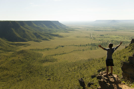 Man with open arms against the wind admires the mountains landscape on the sunrise
