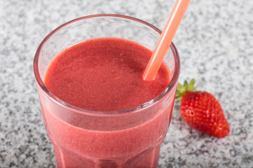 Glass with strawberry cocktail on granite board