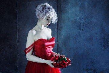 young magnificent woman in red dress holds a wreath of roses. Textured background