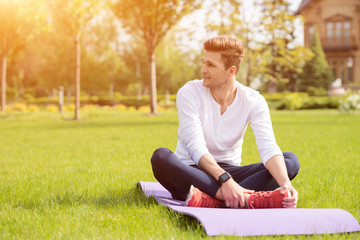 Attractive sportsman doing yoga on grass