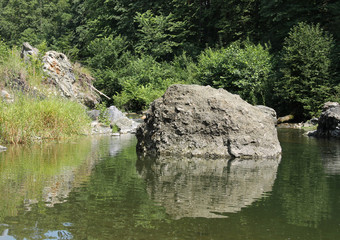Naklejka na ściany i meble big rock in the river reflecting on the water surface