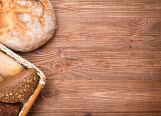 Assortment of baked bread on wooden table background.