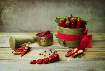 Still life with red chili pepper placed in antique Hun copper,paprika in a copper cup and slices of chilies on rustic wooden table