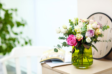 Vase with fresh roses in the room