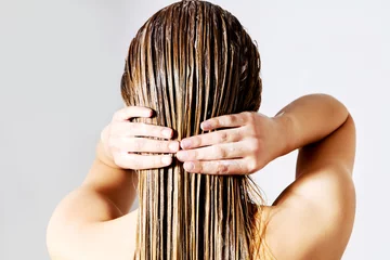 Woman applying hair conditioner. Isolated on white. © Piotr Marcinski