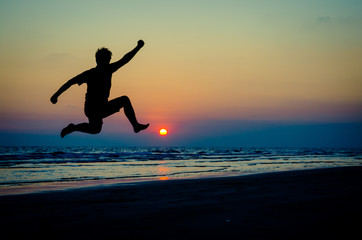 Obraz na płótnie Canvas silhouette of a happy man jumping on a sunset
