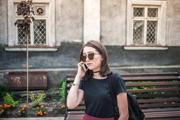 Girl in sunglasses talking on a phone, smart phone in the city, outdoors.