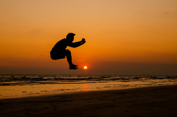 silhouette of a happy man jumping on a sunset