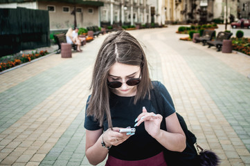 Girl in sunglasses using phone, smartphone in the city, outdoors. She communicates in a social network. She reads the news - 114946725