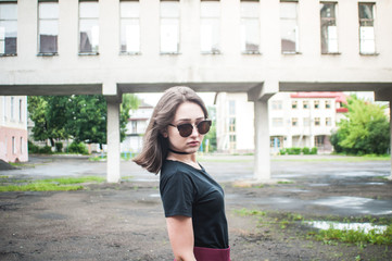 A young girl with beautiful hair and dress a black shirt waiting for friends. She straightens hair at school. The girl walk in a city. Pretty Girl. Wind develops hair