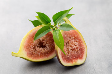 Whole figs and one fig sliced in half on top of a gray table.