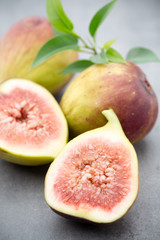 Whole figs and one fig sliced in half on top of a gray table.