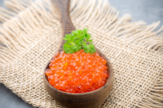 Salmon caviar with spoon on gray background.