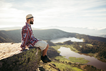Man sitted in a rock looking at the lake in the mountains