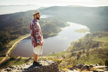 Fototapeta na wymiar Man with hat standing in the top of a mountain with a lake