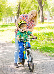 Fototapeta premium young mother dresses her son bicycle helmet