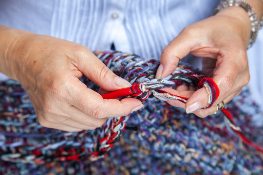 Women hands crochet multicolored woolen carpet