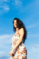 Woman with a dress smiling with a blue sky in the background