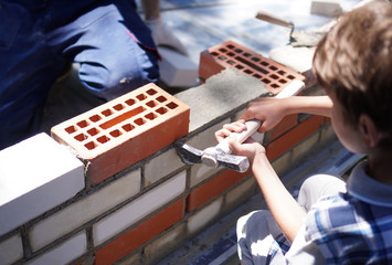 Little boy learning brick layng. upper view.