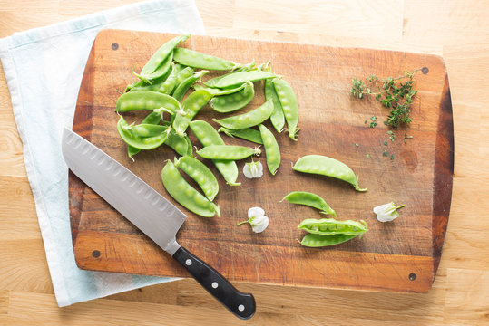 Garden Fresh Snow Peas with thyme on rustic chopping board