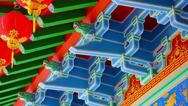 Intricate and traditional ornamentation inside a Chinese Buddhist temple including bold colors, paper lanterns and a dragon motif.