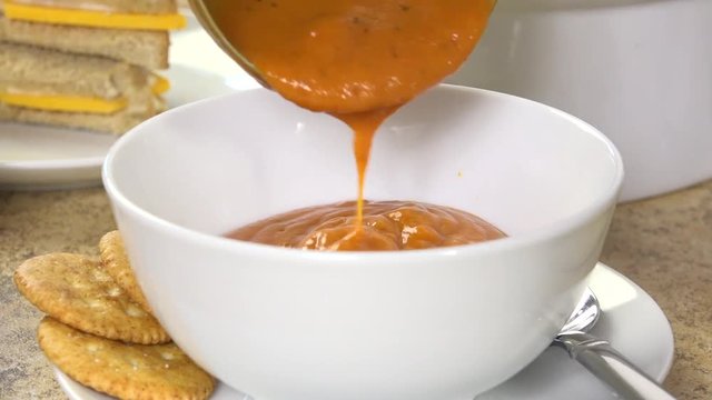 Ladling thick tomato bisque into a bowl

