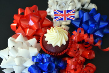 UK celebration cake, party food with red, white and blue cupcake and british flag.  Celebration, patriotism and holidays concept - close up of glazed muffin decorated with british flag