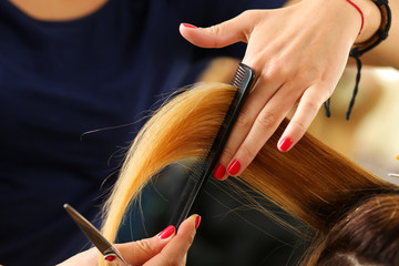 Female hairdresser hold in hand lock of blonde hair - Powered by Adobe