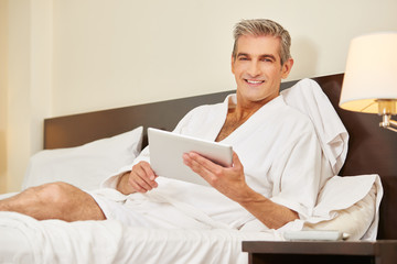 Mann benutzt Tablet im Hotelzimmer