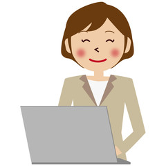 パソコンの前のベージュのスーツの女性　上半身　笑顔