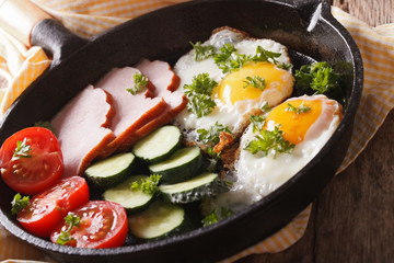 fried eggs with ham and fresh vegetables close-up in a frying pan. horizontal
