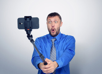 Funny bearded man in tie making selfie with a stick