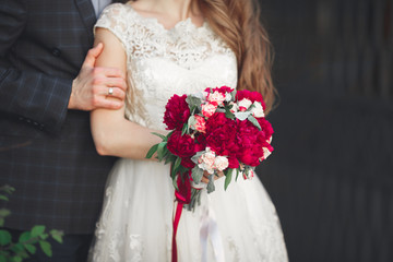 Wedding couple hugging, the bride holding a bouquet of flowers in her hand, groom embracing