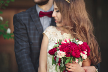 Wedding couple hugging, the bride holding a bouquet of flowers in her hand, groom embracing