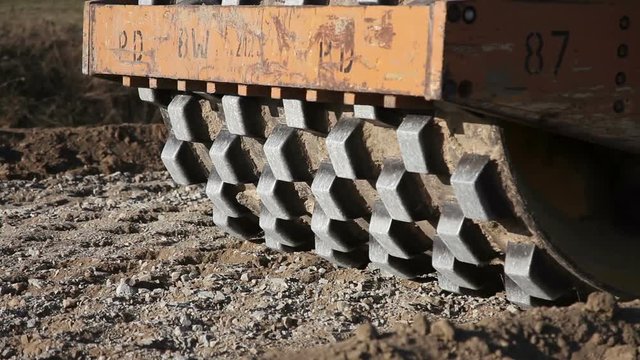 Steamroller working at road construction site compacting gravel
