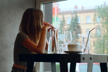 Pretty young girl behind the table with cold cocktail, coffee an