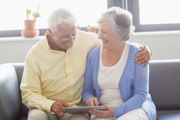 Senior couple using a tablet - obrazy, fototapety, plakaty