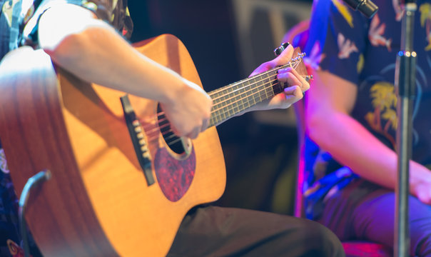 Artist playing wooden guitar on the stage