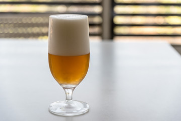 Glass of lager beer on white table