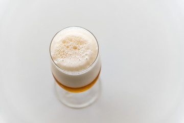 Top view of glass of lager beer on white table