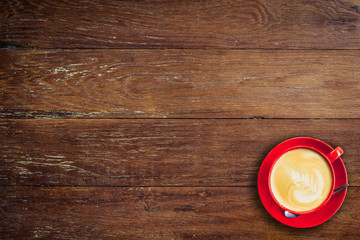 red coffee cup on old wood background with space.