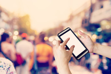 Hand using smartphone and Blurred crowd of people walking throug