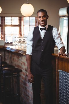 Portrait of bartender standing at bar counter