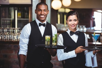 Mixed race waiter and waitress holding a serving tray